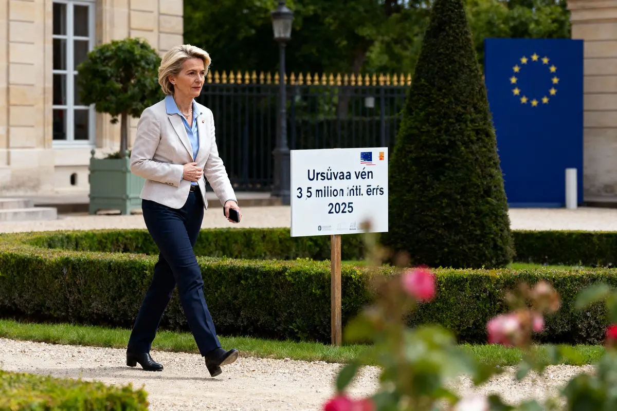 Femme marchant à l'extérieur, pancarte avec texte européen, jardin, bâtiment en arrière-plan.