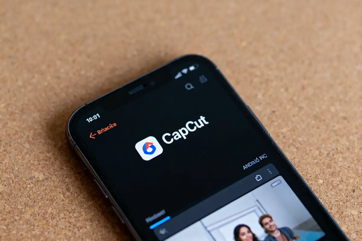 Écran de smartphone affichant l'application CapCut sur fond de table en bois.