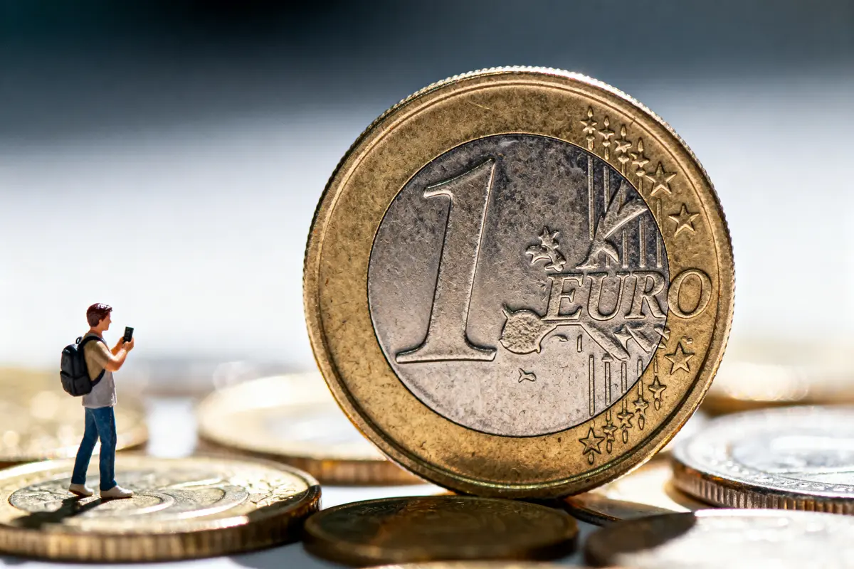 Pièce de 1 euro géante, figurine de personne prenant une photo. Monnaies floues en arrière-plan.
