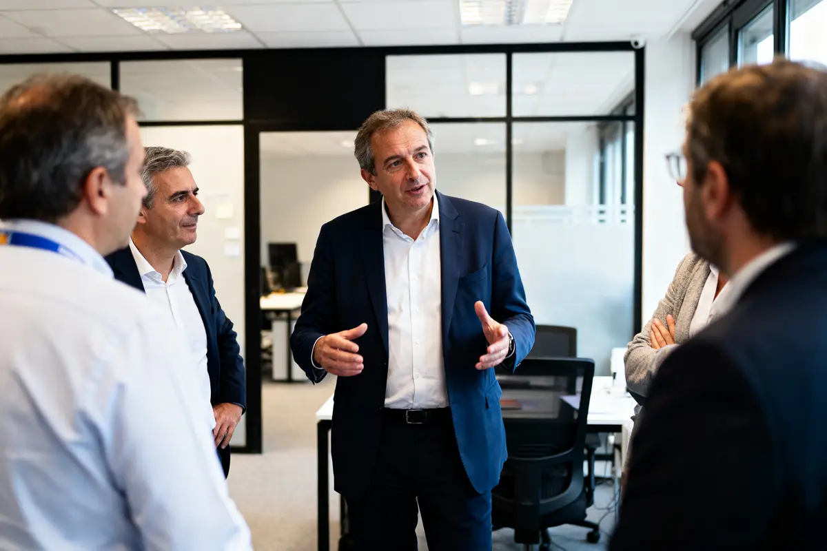 Groupe d'hommes en discussion animée dans un bureau moderne, ambiance professionnelle et collaborative.