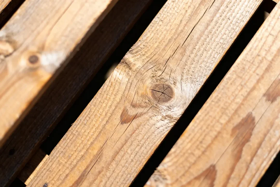 Planches de bois brun avec rainures et nœud, éclairées par un rayon de soleil clin
