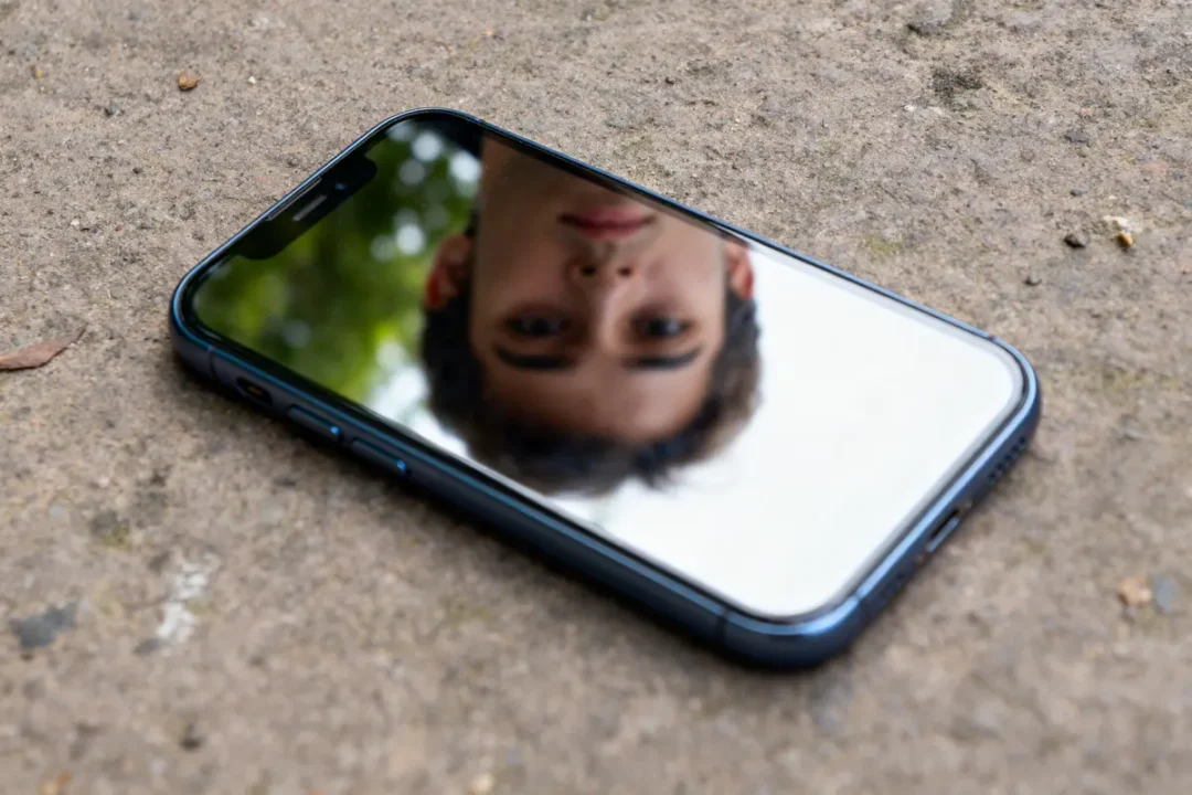 Smartphone au sol reflétant un visage, effet mirrier créant un miroir réaliste