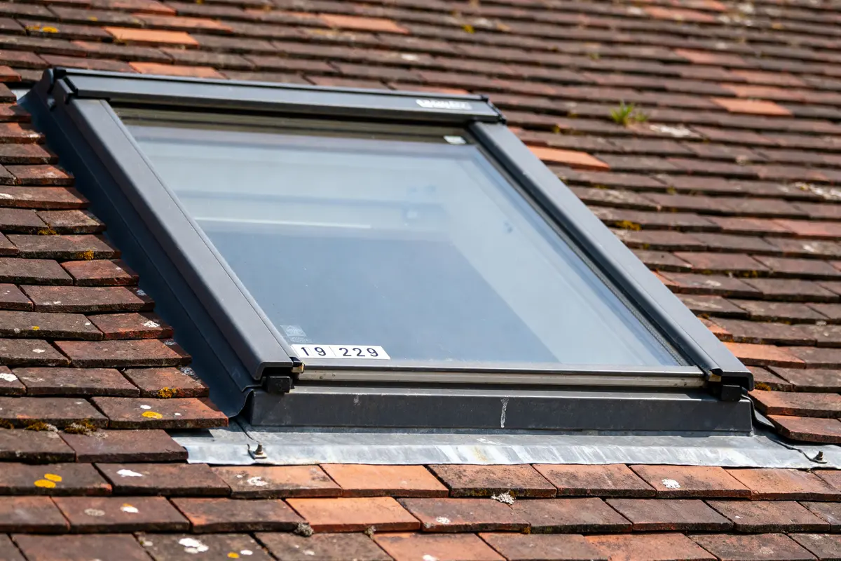 Fenêtre de toit Velux sur toit en tuiles, montrant sa taille Velux optimale.