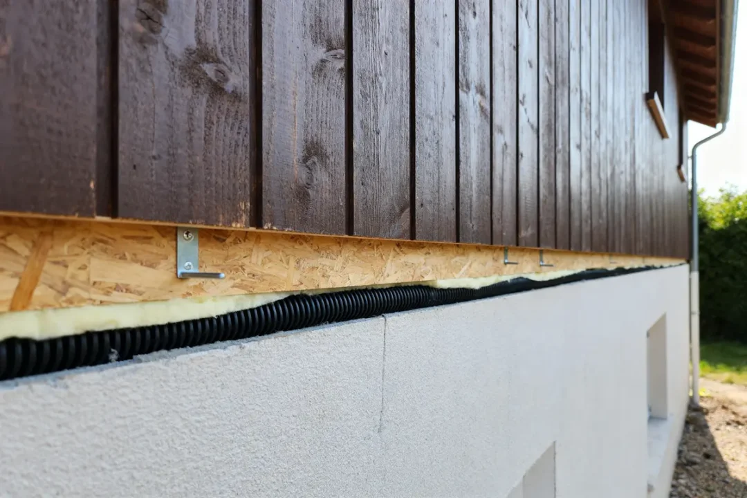 Bardage et clin en bois brun avec isolation sur mur extérieur d'une maison