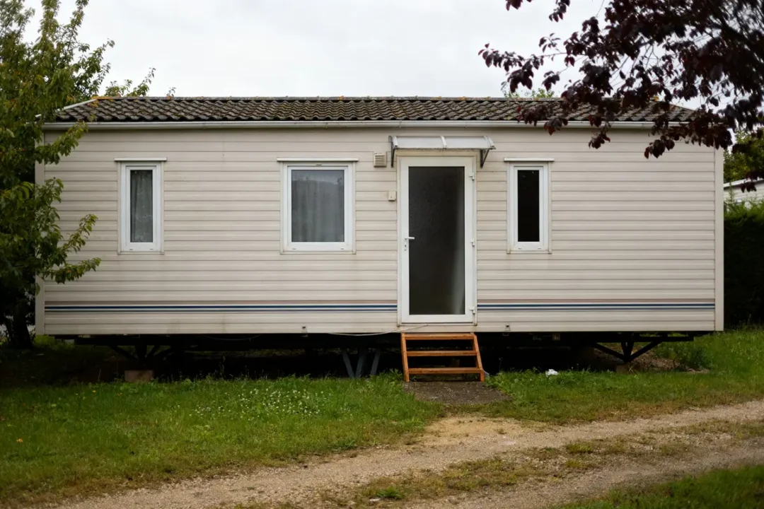 Maison en préfabriqué beige avec escaliers en bois sur terrain gazonné