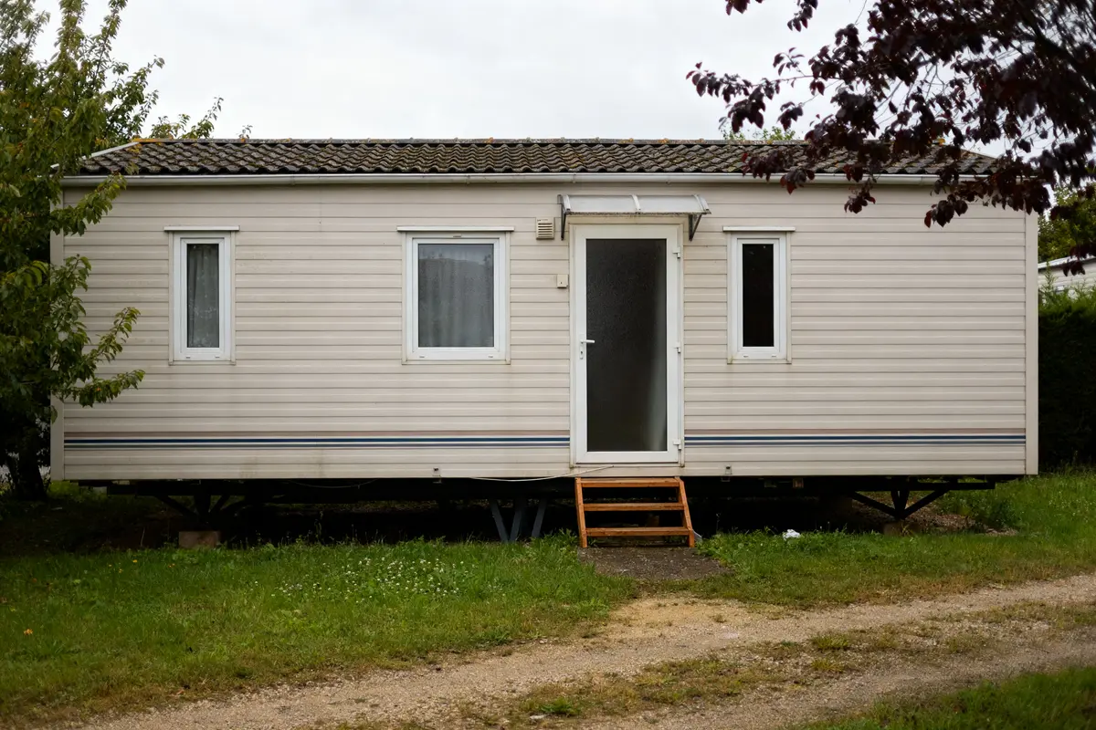 Maison en préfabriqué beige avec escaliers en bois sur terrain gazonné