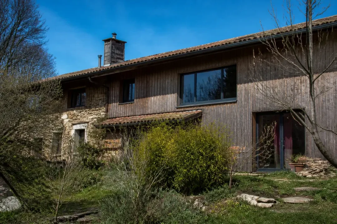 Maison écologique en bois et pierre entourée de nature sur Habitats Durables.
