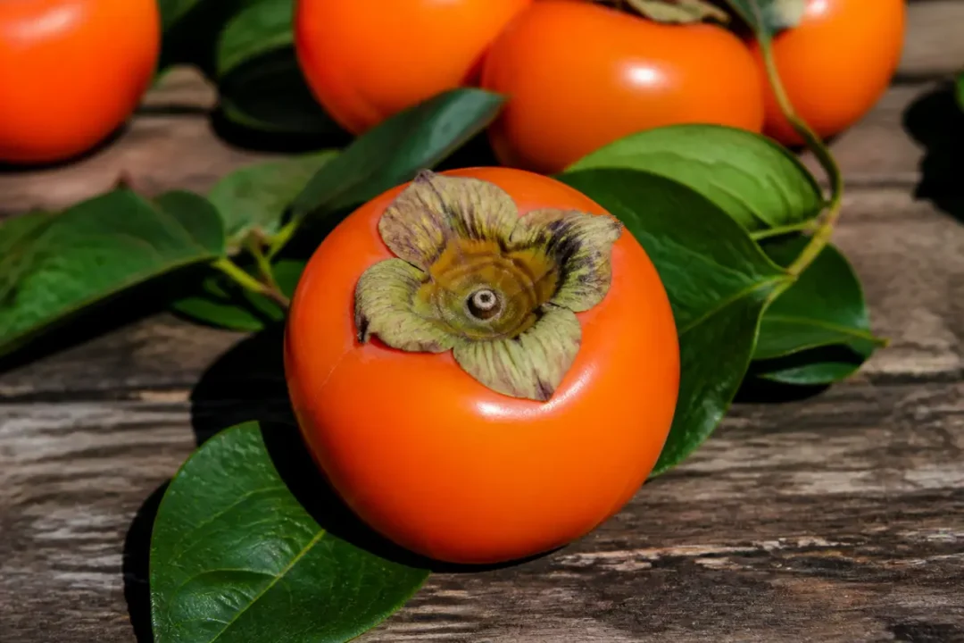 Persimmon kaki fruit orange avec feuilles vertes sur fond en bois