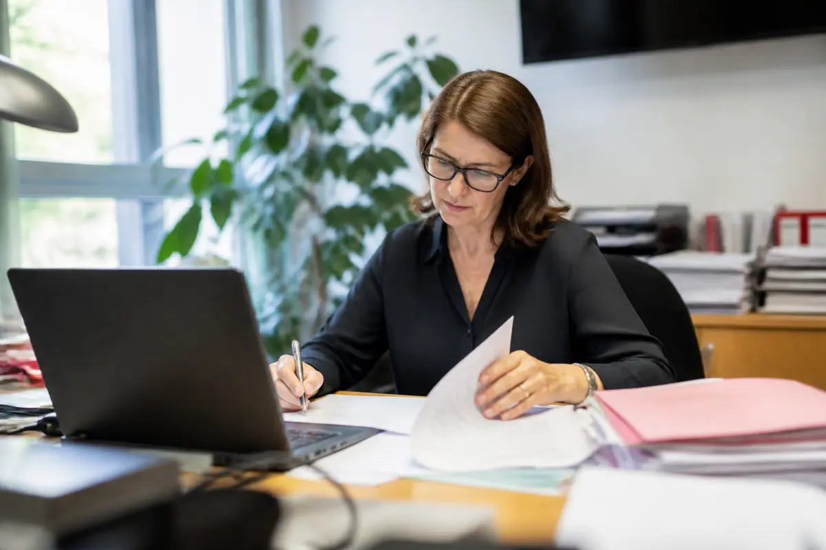 Femme travaillant à son bureau avec ordinateur portable et documents, sujet : salaire de Myriam Seurat